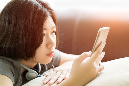 Close up young asian woman short hair listening music from mobile phone on the couch