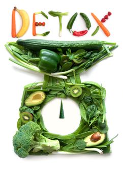 Fruits and vegetables in the shape of kitchen weighing scales with detox on top