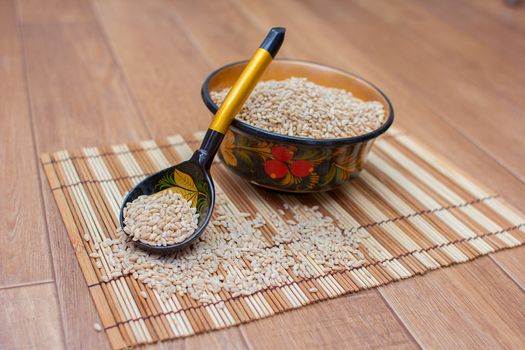 Wooden spoon and cup with the scattered pearl barley, Khokhloma