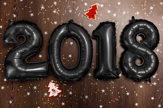 Bright black balloons figures 2018, New Year Balloons with glitter stars on dark wood table background. Christmas and new year celebration