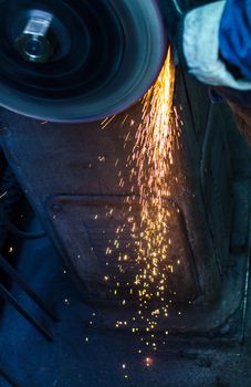 Industrial grinder showers sparks while working with metal.