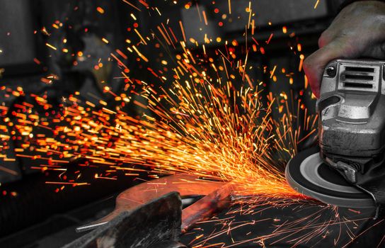 Industrial grinder showers sparks while working with metal.