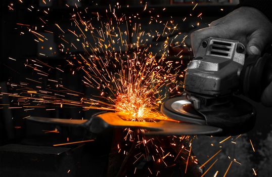 Industrial grinder showers sparks while working with metal.