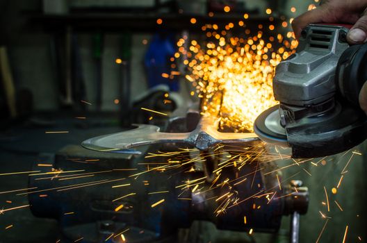 Industrial grinder showers sparks while working with metal.