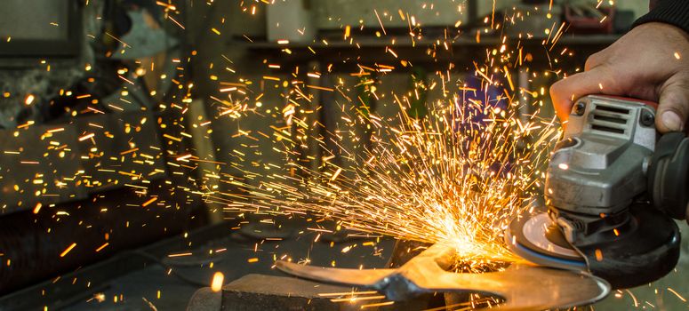 Industrial grinder showers sparks while working with metal.