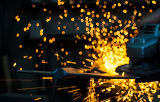 Industrial grinder showers sparks while working with metal.