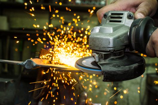 Industrial grinder showers sparks while working with metal.