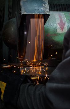 Industrial grinder showers sparks while working with metal.