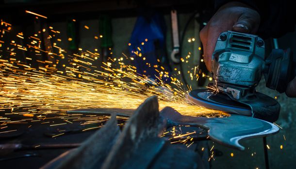 Industrial grinder showers sparks while working with metal.