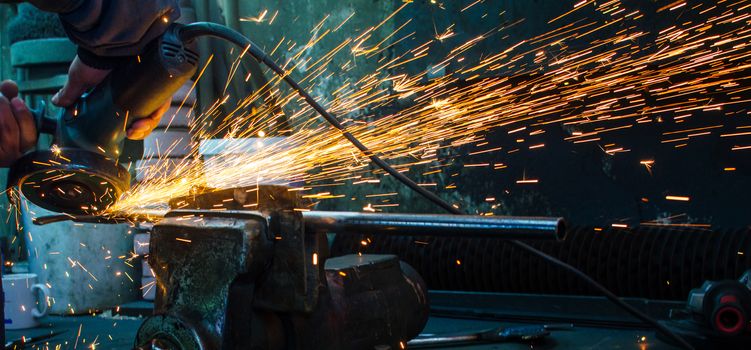 Industrial grinder showers sparks while working with metal.