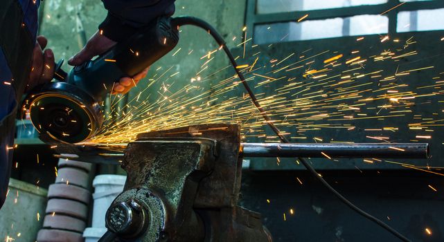 Industrial grinder showers sparks while working with metal.