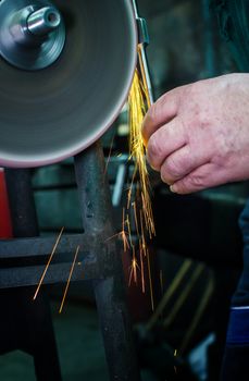 Industrial grinder showers sparks while working with metal.