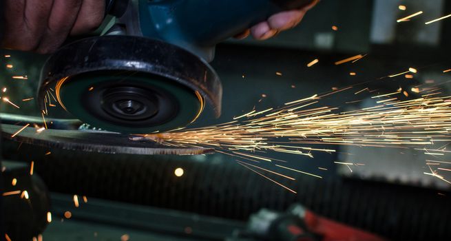 Industrial grinder showers sparks while working with metal.