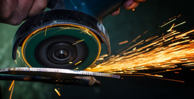 Industrial grinder showers sparks while working with metal.