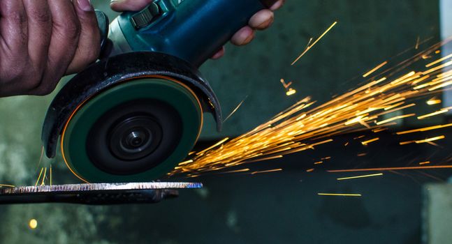 Industrial grinder showers sparks while working with metal.