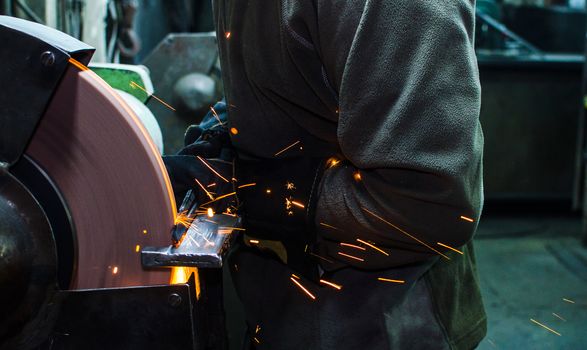 Industrial grinder showers sparks while working with metal.