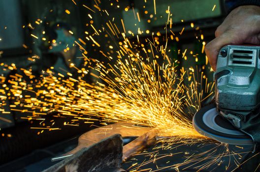 Industrial grinder showers sparks while working with metal.