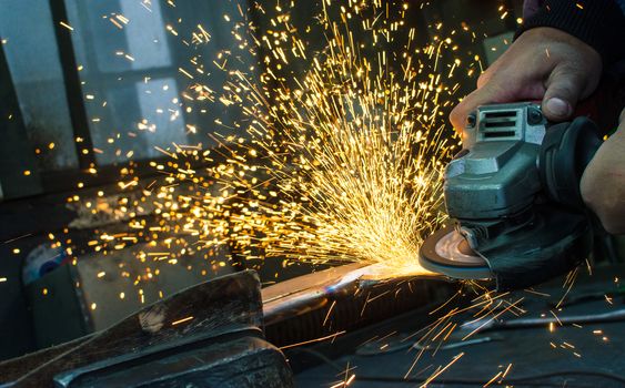 Industrial grinder showers sparks while working with metal.