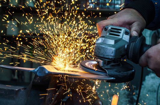 Industrial grinder showers sparks while working with metal.