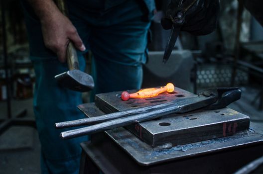 Blacksmith at work, hit with a hammer by a hot metal on the anvil.