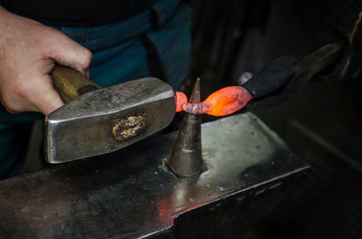 Blacksmith at work, hit with a hammer by a hot metal on the anvil.