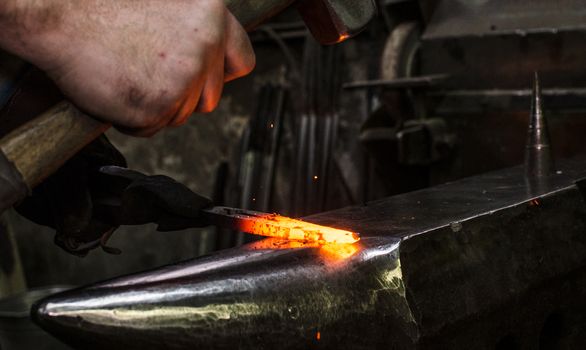 Blacksmith at work, hit with a hammer by a hot metal on the anvil.