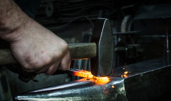 Blacksmith at work, hit with a hammer by a hot metal on the anvil.