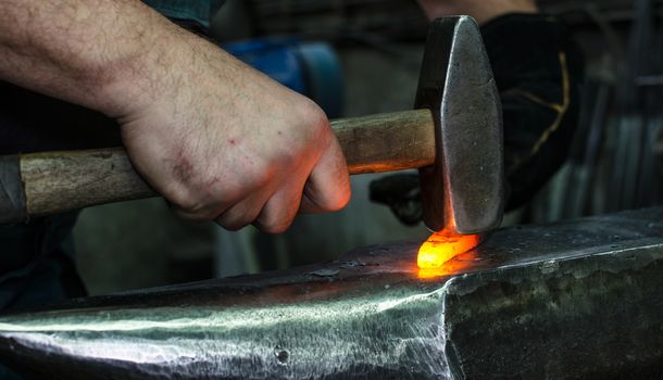 Blacksmith at work, hit with a hammer by a hot metal on the anvil.