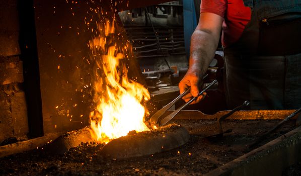 Blacksmith at work, hit with a hammer by a hot metal on the anvil.