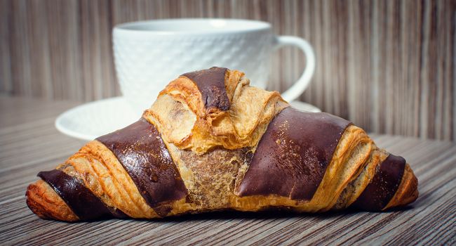 A chocolate croissant with coffee for a hearty breakfast.