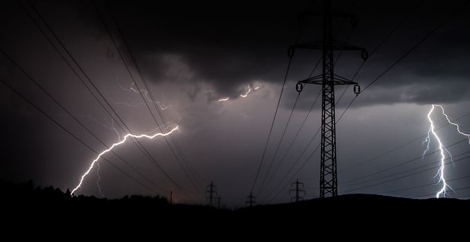 The lightning strikes the high voltage line in a storm.