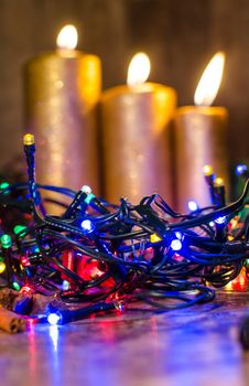Gold candle and different colors lights are classic symbol of Christmas.