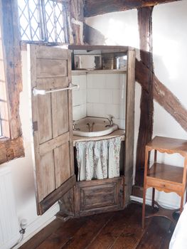 old wooden wash cupboard basin sink closet in corner of english manor house room antique; essex; england; uk