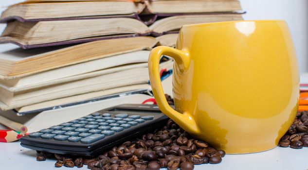 A  pile of books calculator and coffee help in learning.