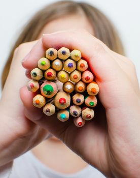 Colored pencils for painting in children's hands on a white background.