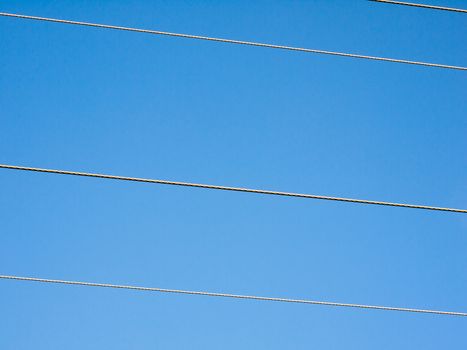 electricity pylon wires cutting across blue sky background; essex; england; uk