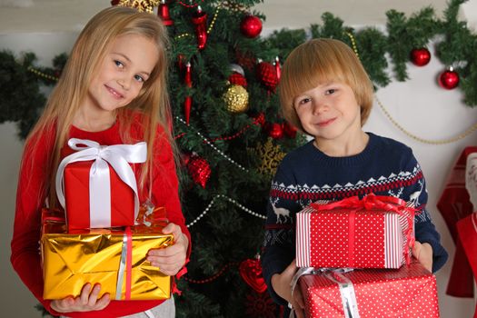 Portrait of two happy children with Christmas gift boxes and decorations. Two kids having fun at home