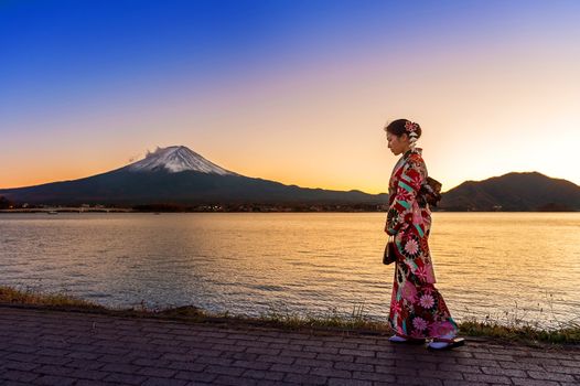 Asian woman wearing japanese traditional kimono at Fuji mountain. Sunset at Kawaguchiko lake in Japan.