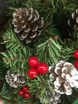 Faux Christmas tree decorated with snow covered pine cones and red berries