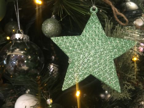 Green glitter encrusted star shape hanging on a Christmas tree