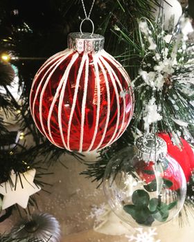 Christmas baubles and other seasonal decorations hang on a snowy Christmas tree