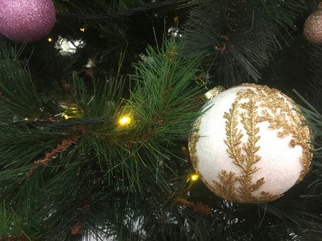 Gold embellished Christmas tree bauble hangs on the branch of a pine, Christmas tree 