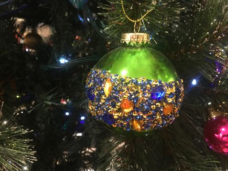 Beautiful green Christmas tree bauble is embellished with amber, blue and gold faceted crystals hangs on a tree to delight in the Christmas holiday season.