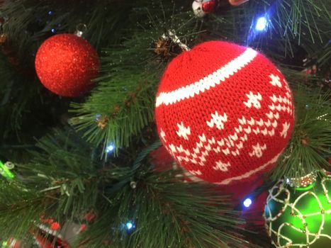 Christmas tree decorations adorn a Christmas tree.  Focus to foreground bauble with a red white winter knit pattern.  Shallow dof.