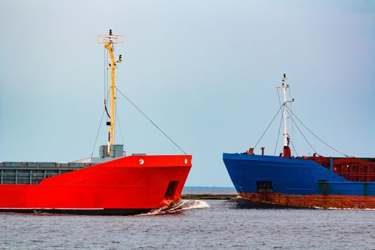 Orange cargo ship sailing past the blue bulk carrier