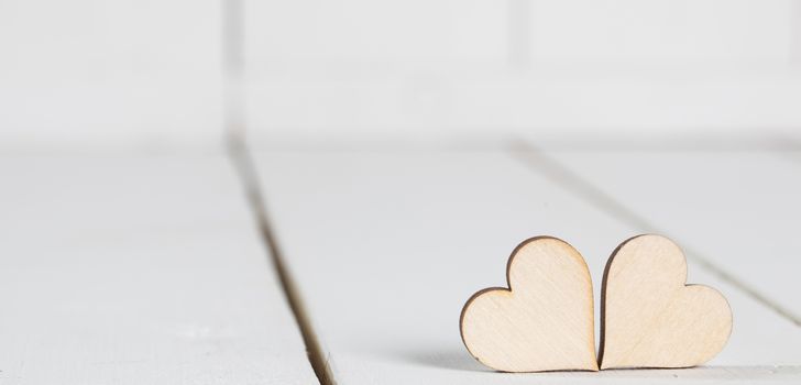 Two wooden Valentine day hearts on white wooden background