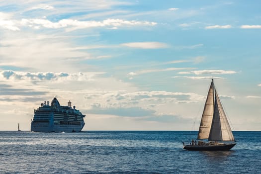 Blue sailboat traveling against the cruise liner in Riga