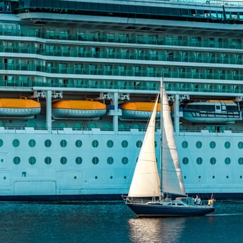 Blue sailboat traveling against the cruise liner in Riga