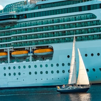 Blue sailboat traveling against the cruise liner in Riga