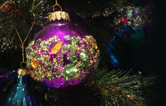 Bejewelled encrusted crystal decorated Christmas baubles hang on a tree